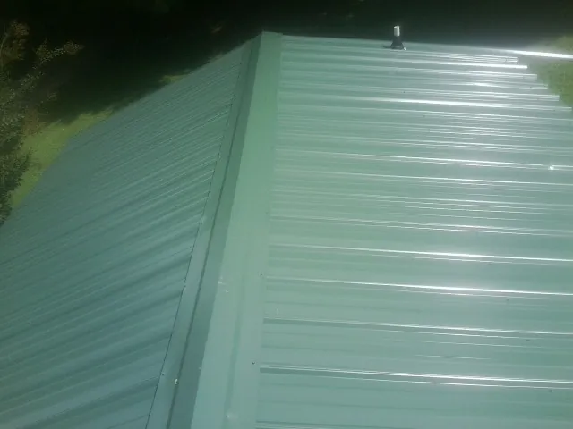 New green metal panels meeting at the ridge of a roof — Flat Roof Repair work by our crew in Snowmass
