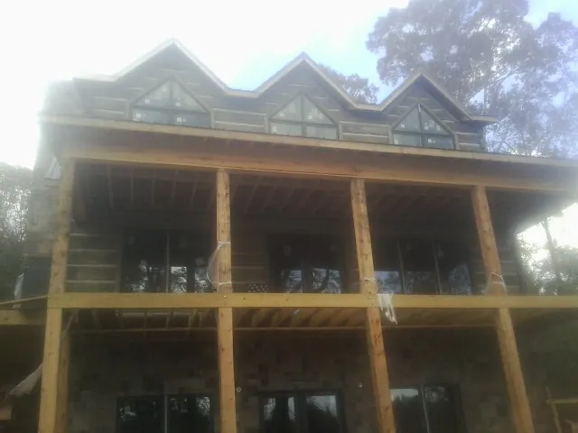 Dormers and porch framing on a large log home under construction — Roof Coating work by our crew in Snowmass