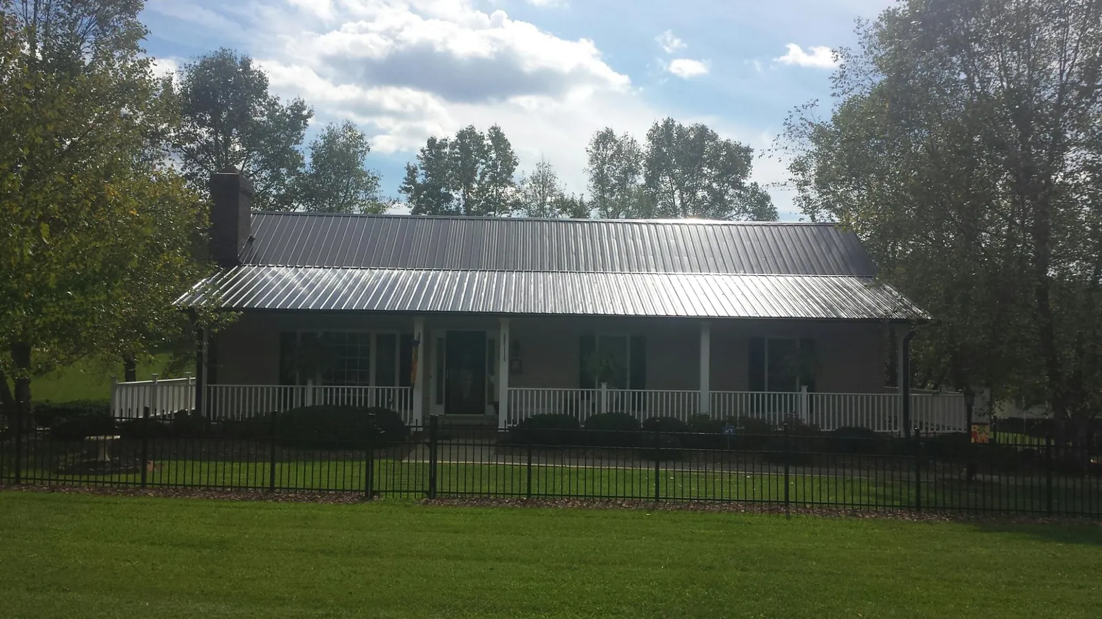 Gray metal roof on a brick ranch with a full width front porch — Gutter Guard Installation work by our crew in Snowmass