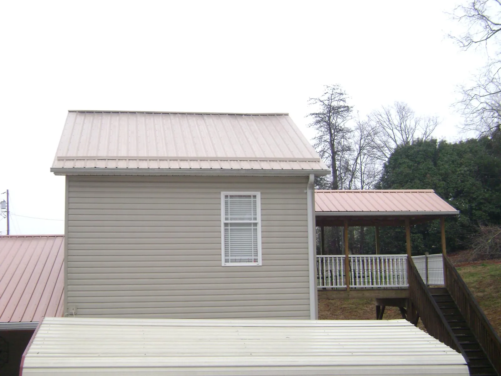 Tan metal roofs on a two story addition and attached porch, from a Roof Replacement job in Snowmass