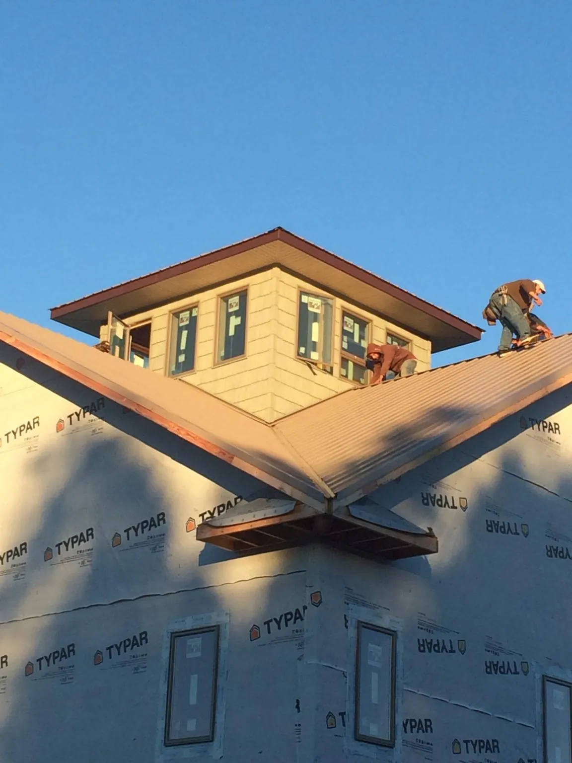 Roofers working around a rooftop cupola on a new metal roof at sunset — Roof Waterproofing in Snowmass by Roofing Brothers